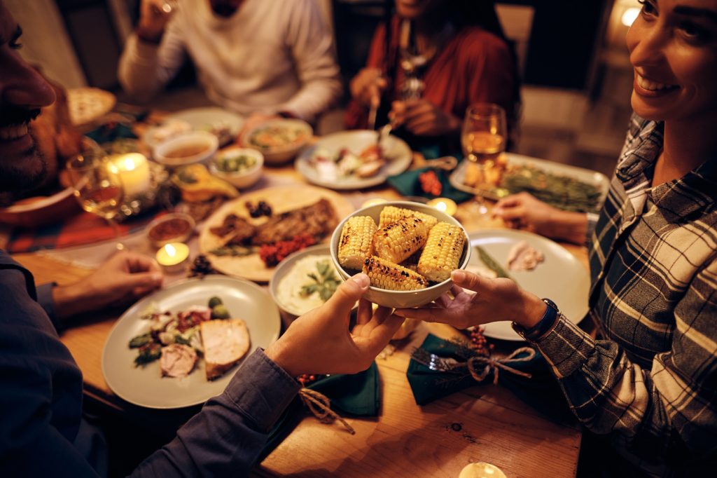 Close up of couple passing food during Thanksgiving dinner at dining table.